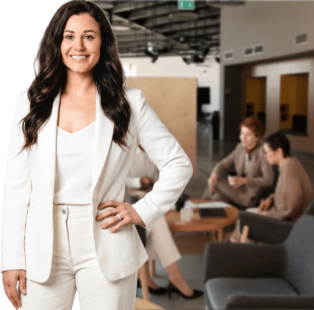 Kaitie Brinston in a white blazer, with colleagues talking in the background