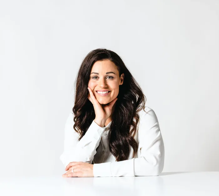 Kaitie Brinston at her desk, chin resting on her hand, smiling